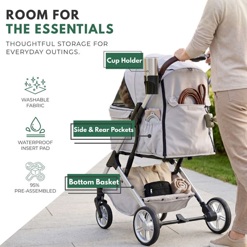 The image shows a pet stroller with storage compartments being pushed along a paved walkway. It includes labels and text highlighting features such as a cup holder, side and rear pockets, a bottom storage basket, washable fabric, a waterproof inner liner, and the fact that it comes "95% pre-assembled."